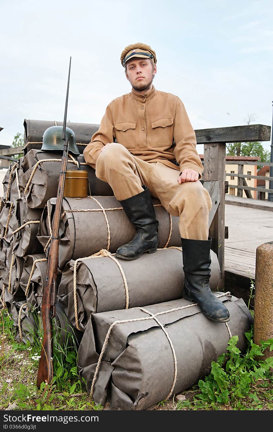 Soldier with helmet and gun sitting on the bundles. Costume accord the times of World War I. Photo made at cinema city Cinevilla in Latvia. Soldier with helmet and gun sitting on the bundles. Costume accord the times of World War I. Photo made at cinema city Cinevilla in Latvia.