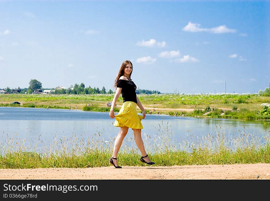 Woman walking near the lake on a sunny summer day. Woman walking near the lake on a sunny summer day