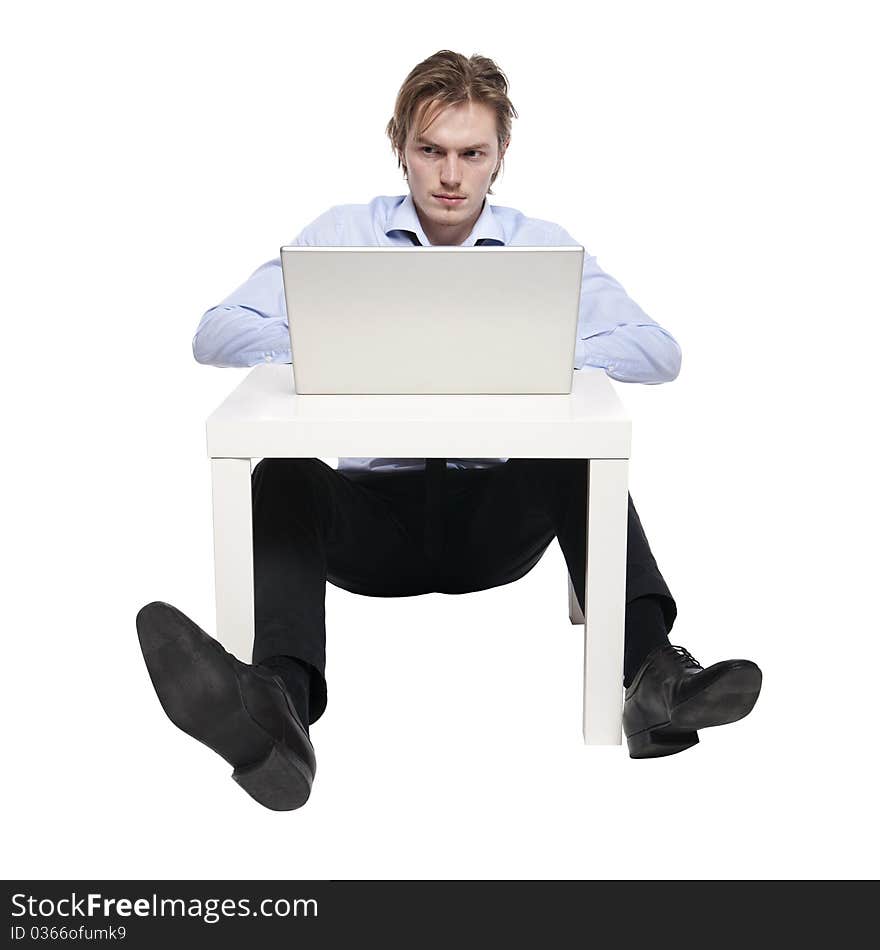 Young businessman, office worker or student with laptop, Studio photo of young man sitting at funny small table. Young businessman, office worker or student with laptop, Studio photo of young man sitting at funny small table.