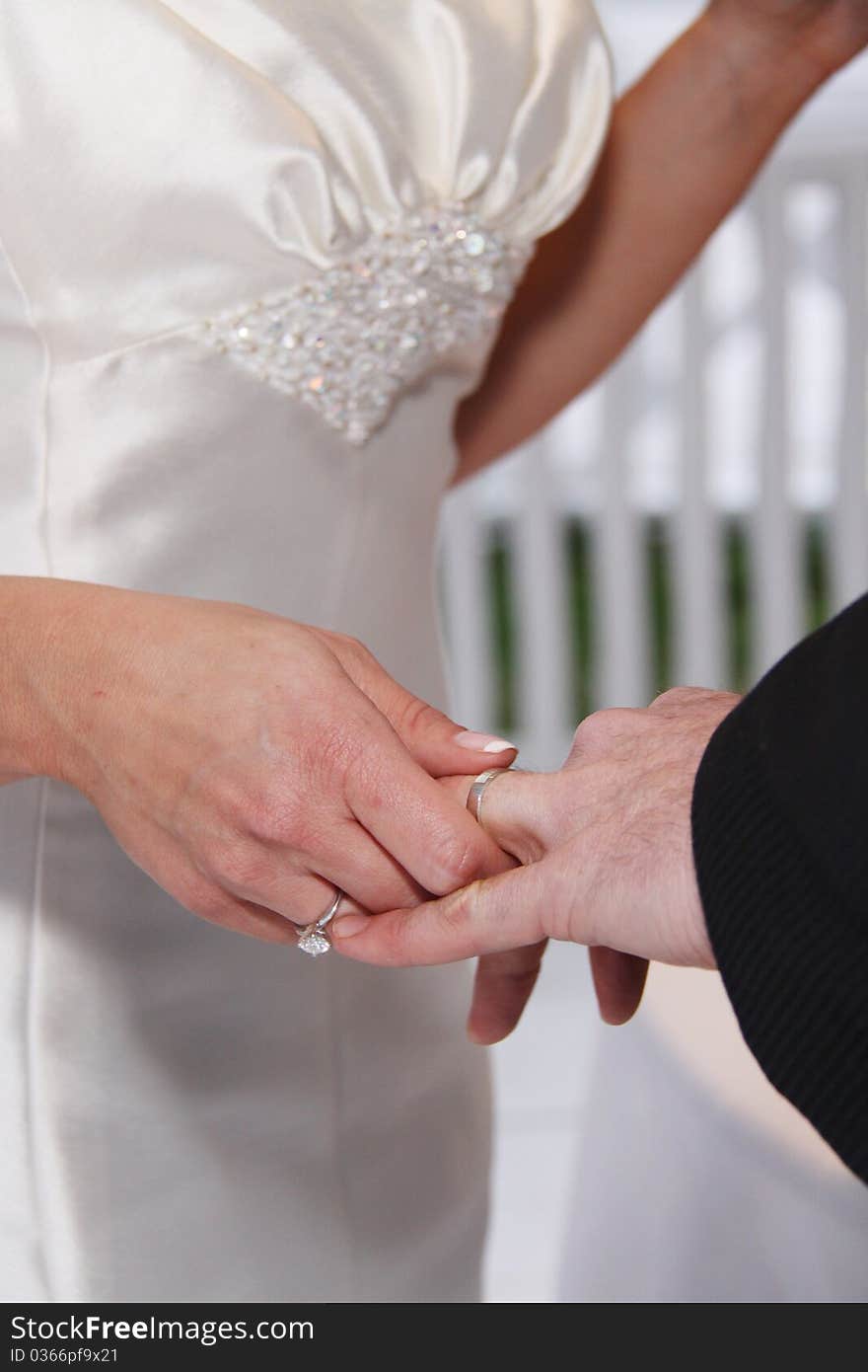 Husband and wife's hands with wedding ring. Bride puts silver band on grooms finger. Husband and wife's hands with wedding ring. Bride puts silver band on grooms finger.