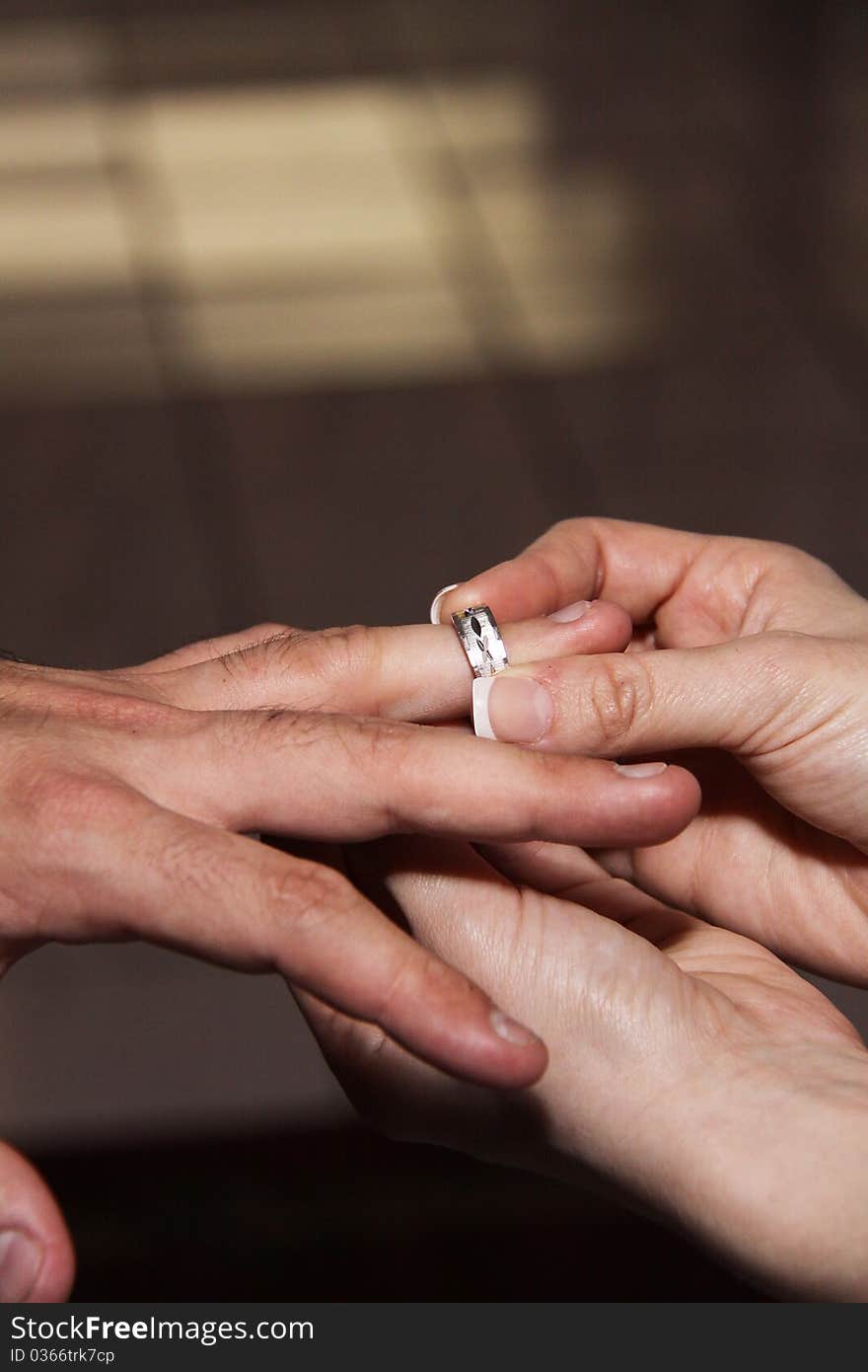 Husband and wife's hands with wedding ring. Bride puts silver band on grooms finger. Husband and wife's hands with wedding ring. Bride puts silver band on grooms finger.