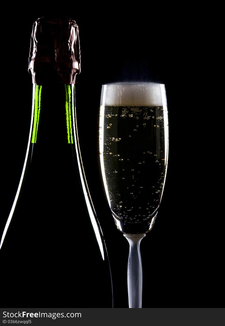 Tiny bubbles in a glass of champagne beside a full bottle.