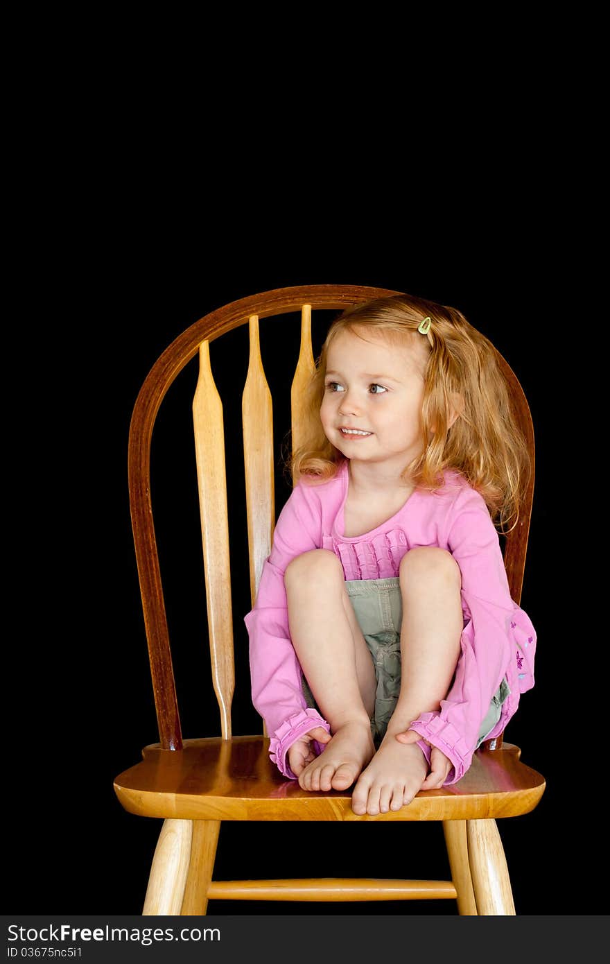 A cute girl sitting on a chair/stool. She has a very unique facial expression. A cute girl sitting on a chair/stool. She has a very unique facial expression.