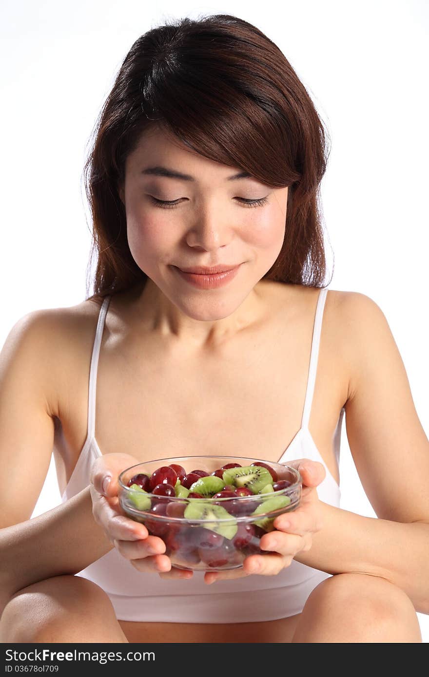 Close up of beautiful, young oriental girl, looking down at a bowl of fruit she is holding in her hands. Close up of beautiful, young oriental girl, looking down at a bowl of fruit she is holding in her hands.