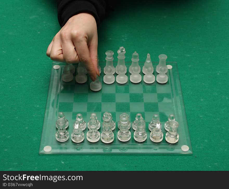 A female hand making the first move on a chess match. A female hand making the first move on a chess match.