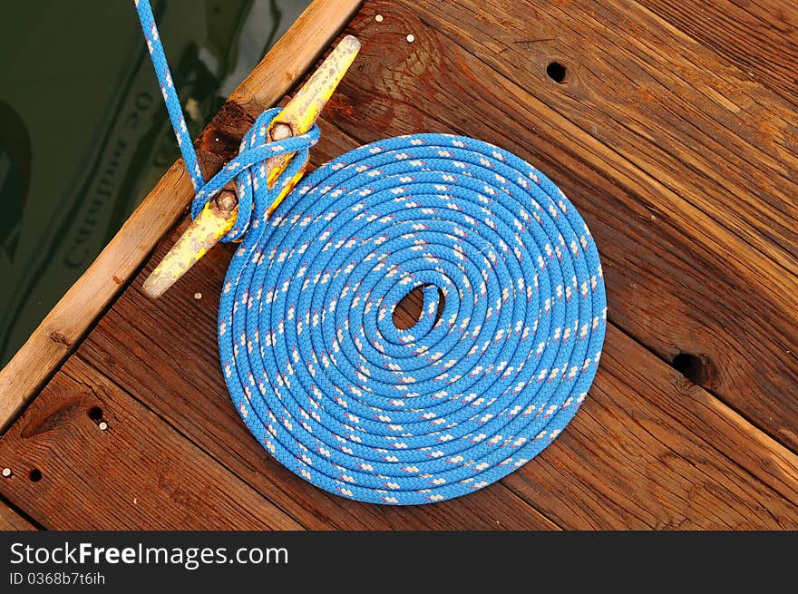 Boat tied to dock, nicely coiled rope, tied off, made fast, blue rope, neatly coiled rope. Boat tied to dock, nicely coiled rope, tied off, made fast, blue rope, neatly coiled rope