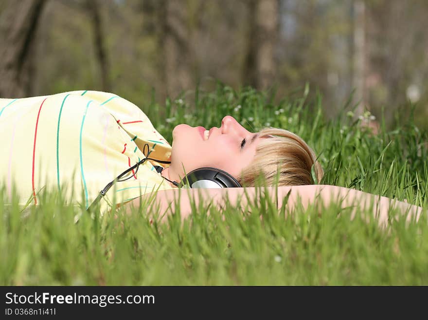 Beautiful young girl with headphones, listen to music on meadow. Beautiful young girl with headphones, listen to music on meadow