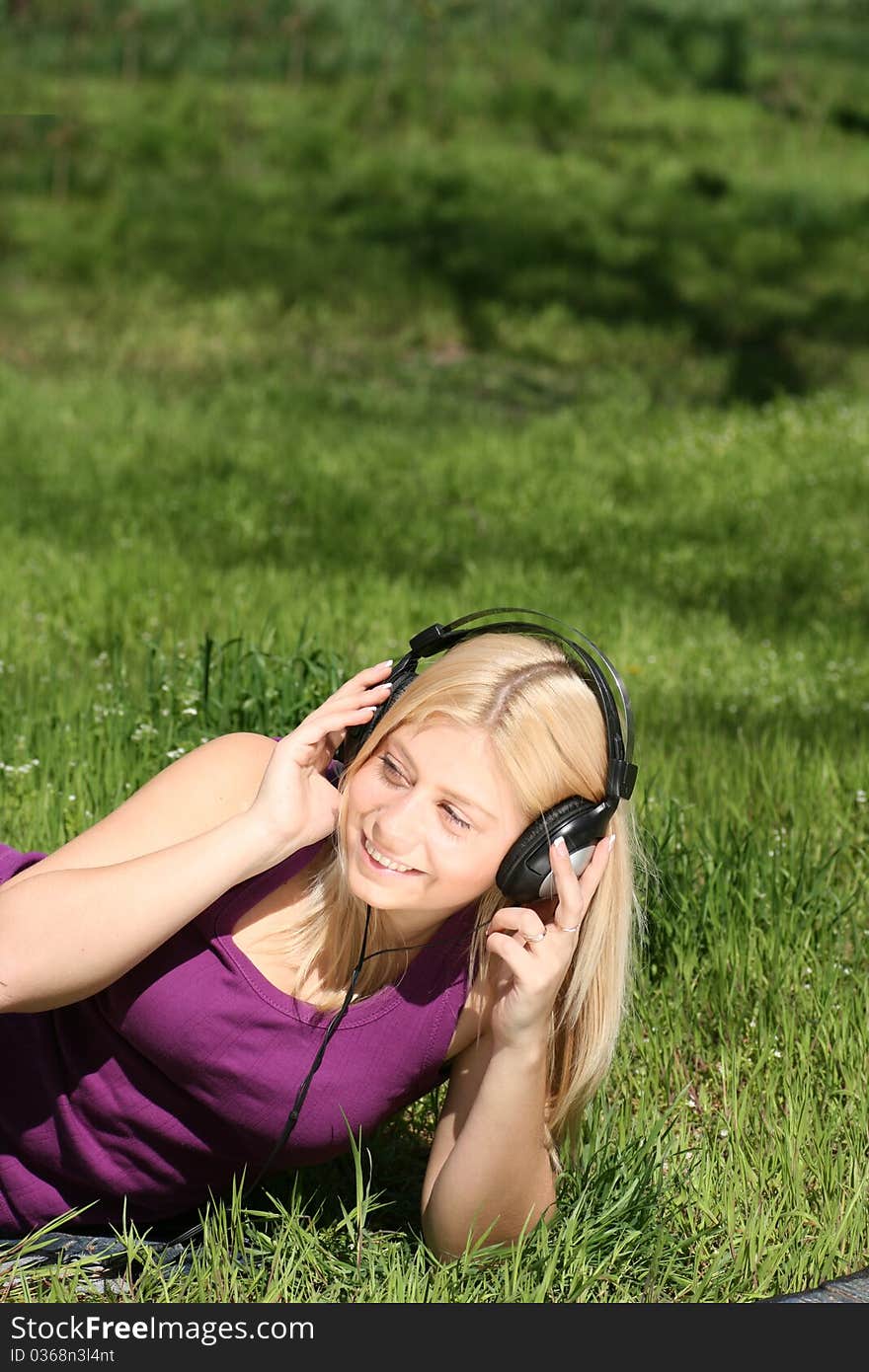 Beautiful young girl with headphones, listen to music on meadow. Beautiful young girl with headphones, listen to music on meadow