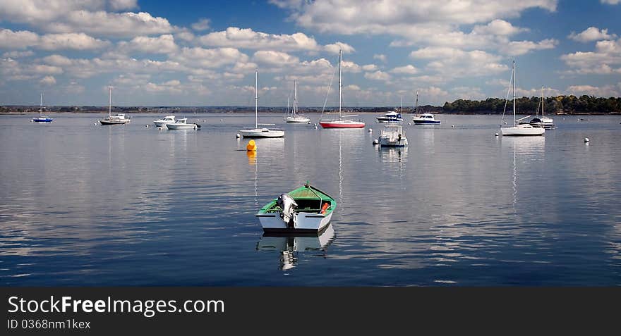 Moored colored boats on the sea under blue sky and smart clouds