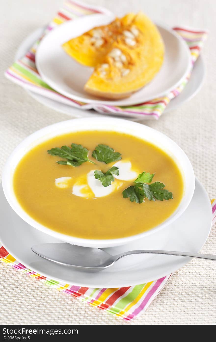 Pumpkin soup in a bowl and two pieces of pumpkin