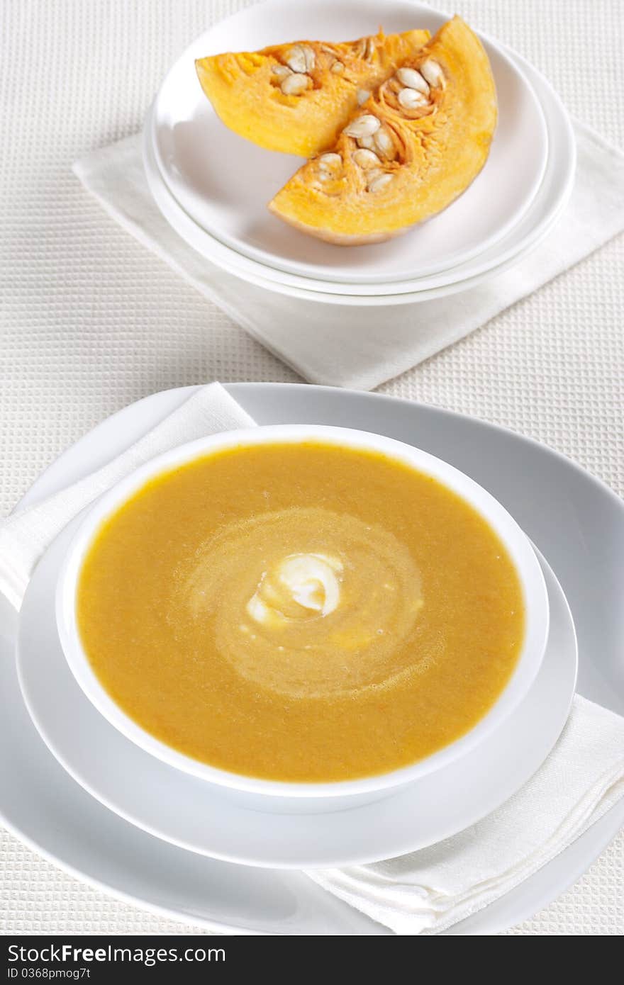 Pumpkin soup in a bowl and two pieces of pumpkin