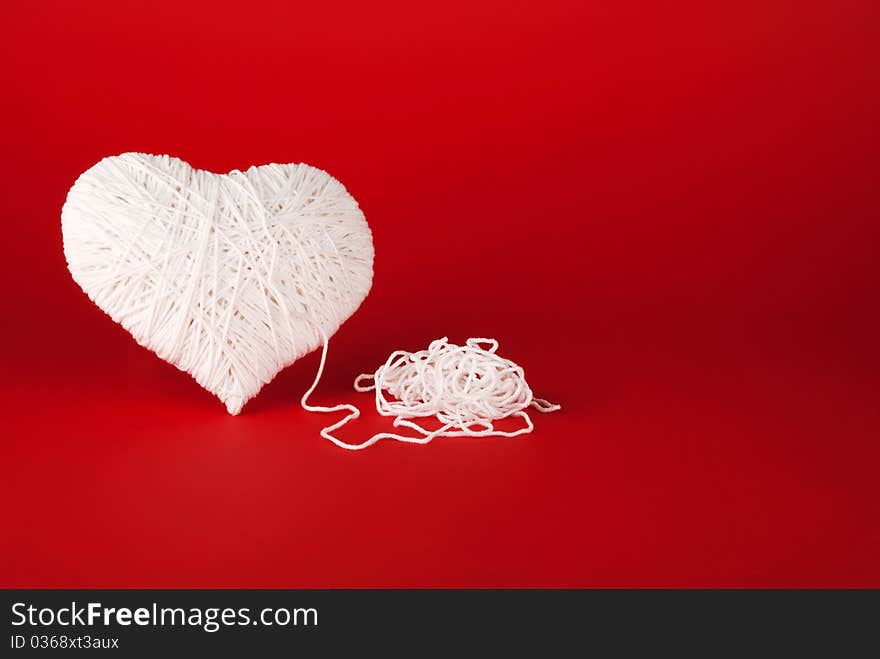 White Heart Made Of Wool On A Red Background.