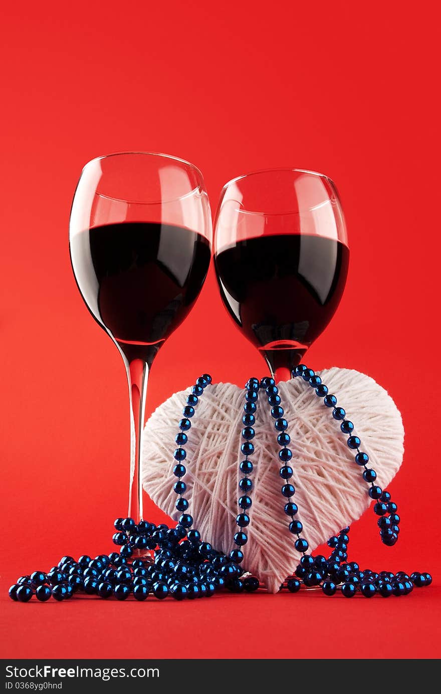 Two glasses of wine and a heart on a red background. Valentine's Day