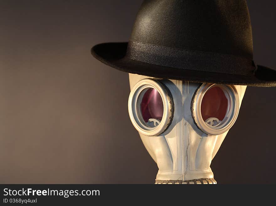 Gas mask with a felt hat closeup on dark background. Gas mask with a felt hat closeup on dark background