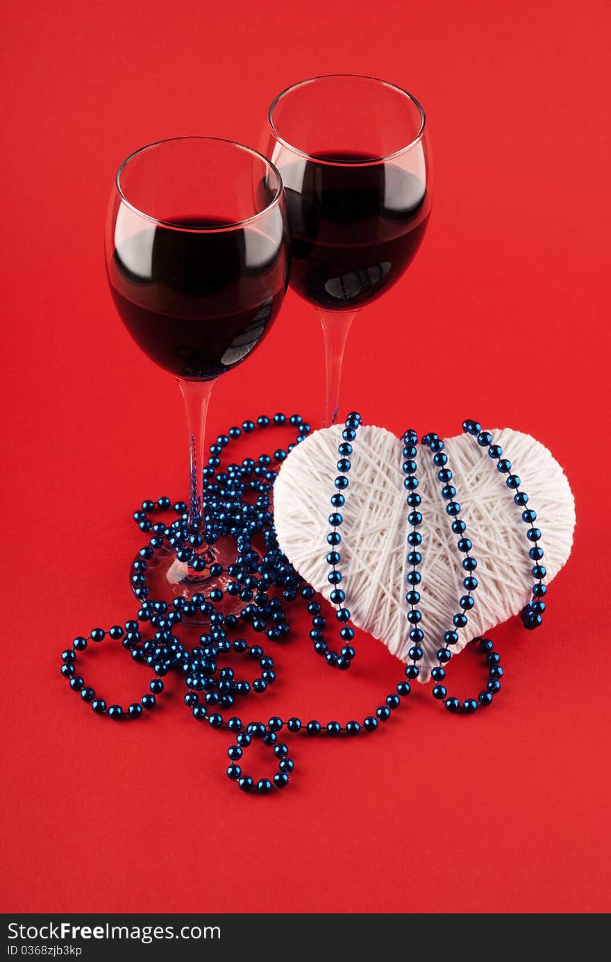 Two glasses of wine and a heart on a red background. Valentine's Day