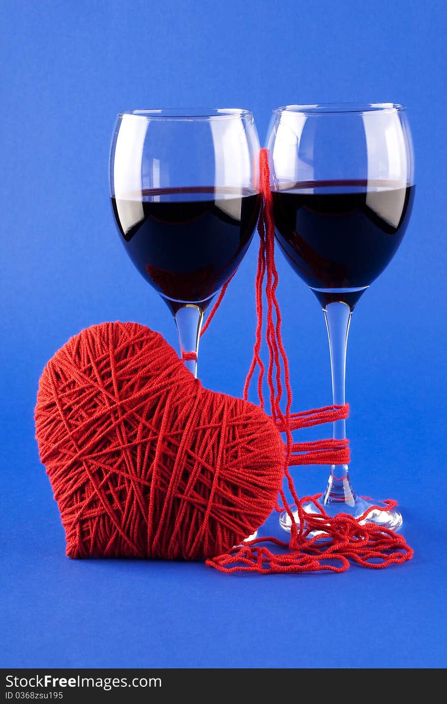 Two glasses of wine and a red heart on a blue background