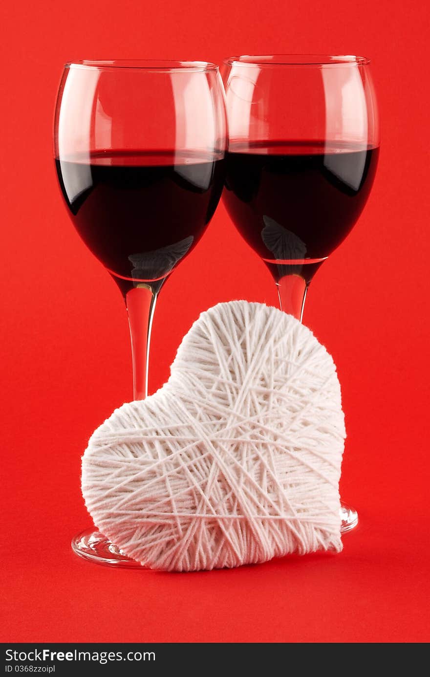 Two glasses of wine and a white heart made of wool