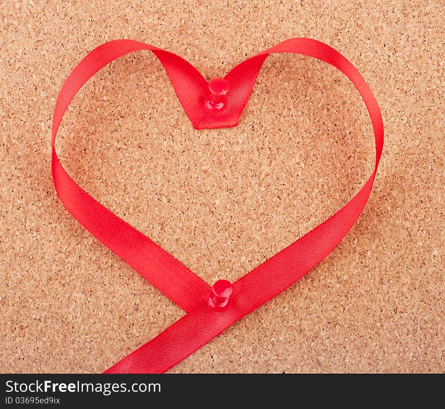 Red heart shaped ribbon pinned to cork board