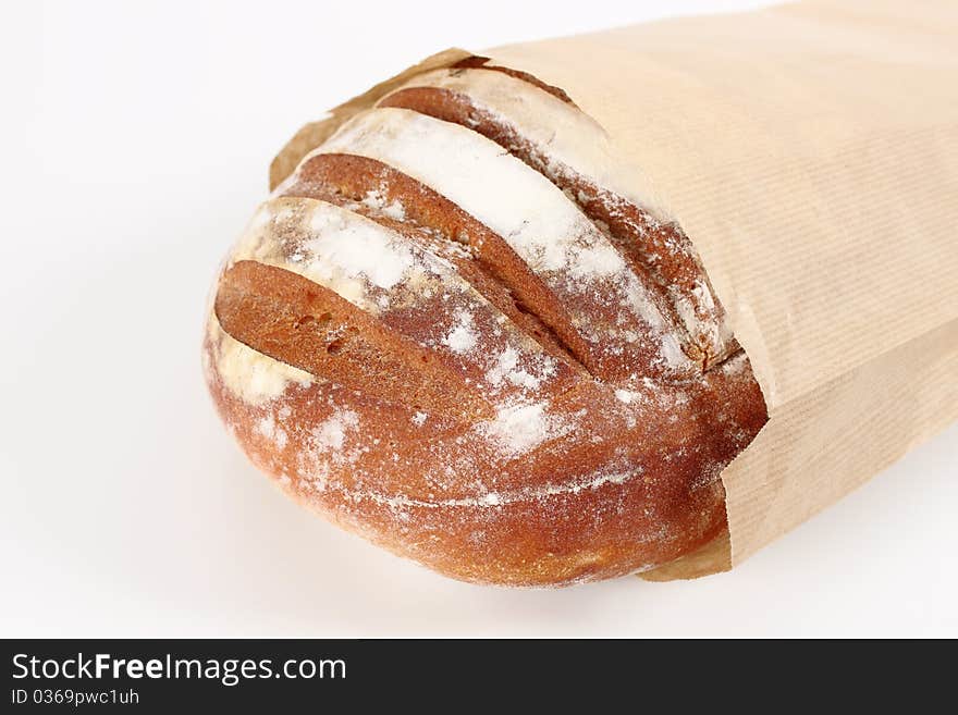 Fresh bread in paper bag in the foreground