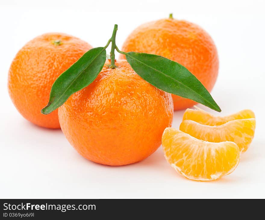 Tangerines with leaves and slices on white background