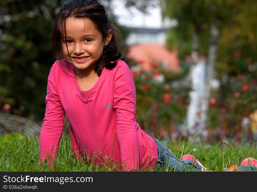 Happy little girl laying on the grass in the park