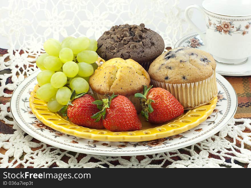 A plate of fresh baked assorted muffins with fresh fruit. A plate of fresh baked assorted muffins with fresh fruit