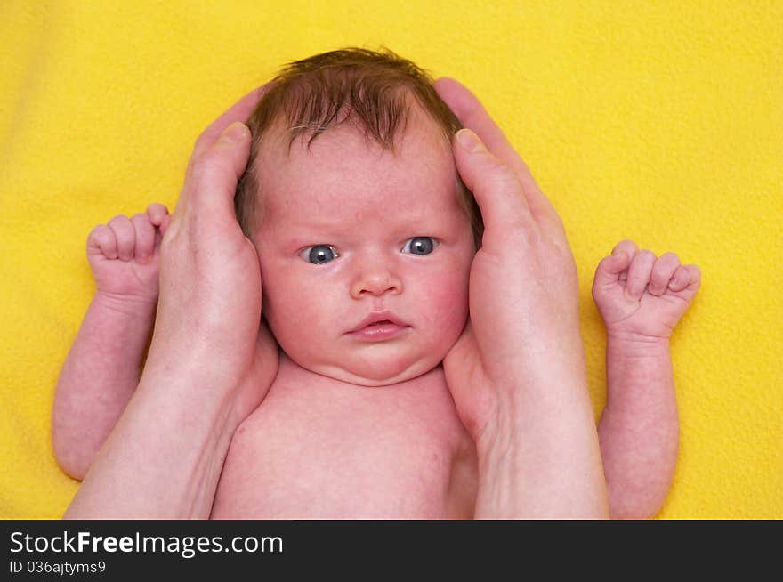 Newborn baby girl over soft yellow towel in mother's hands