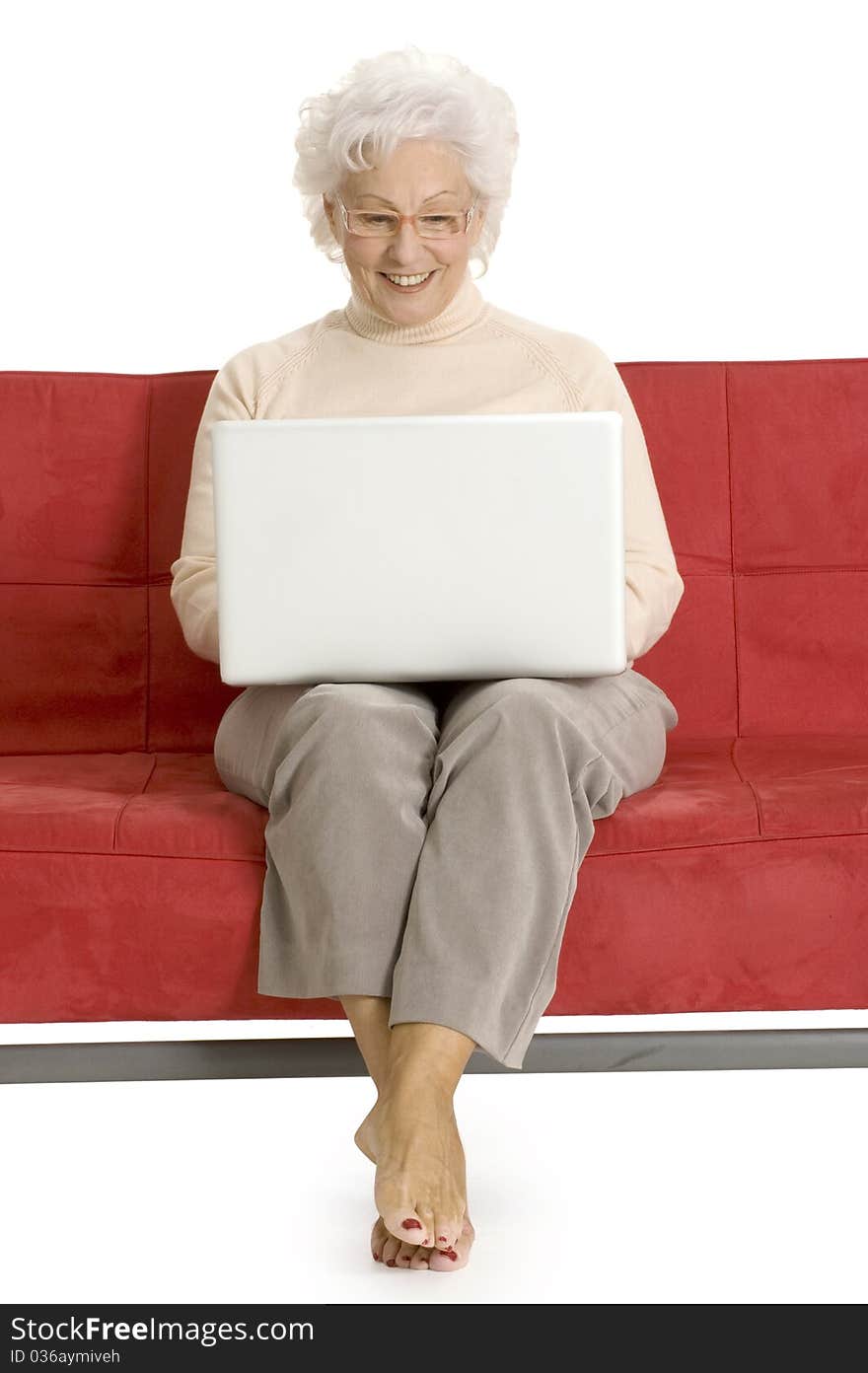 Elderly woman on the couch with laptop in a white background