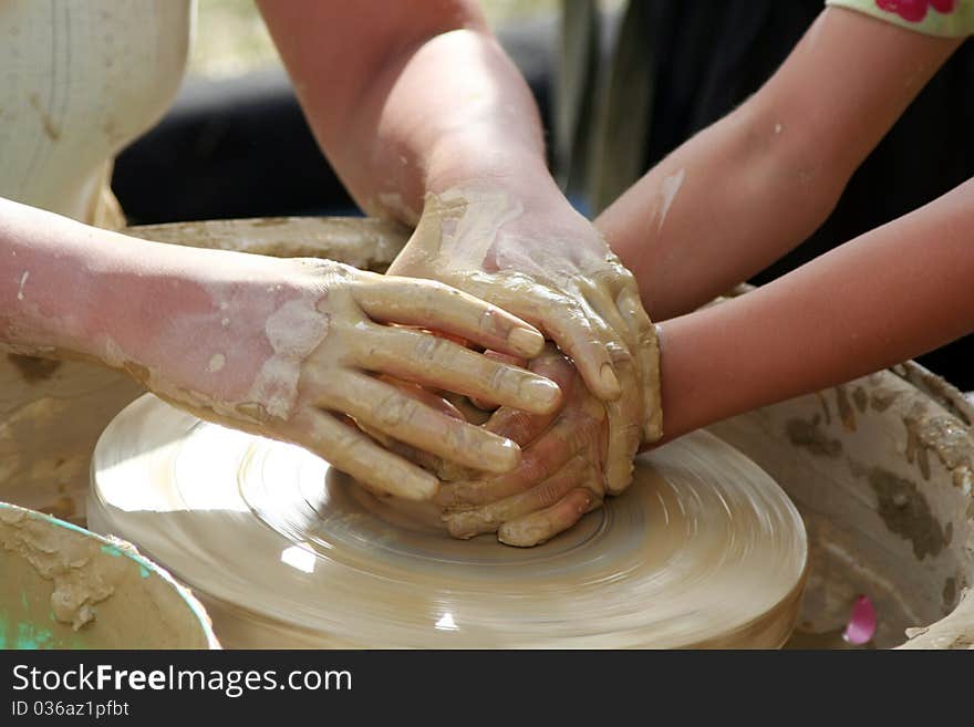 A woman teaches a young girl, that how can she prepares a pot from clay. A woman teaches a young girl, that how can she prepares a pot from clay.