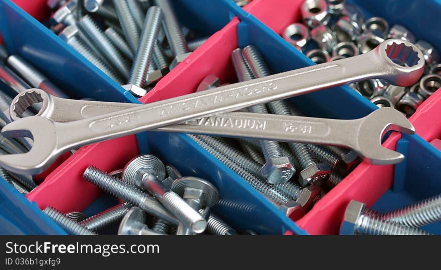 A set of spanners in front of toolbox of bolts and nuts. A set of spanners in front of toolbox of bolts and nuts