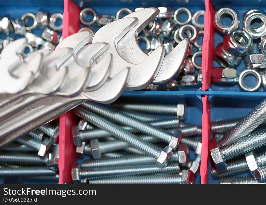 A set of spanners in front of toolbox of bolts and nuts. A set of spanners in front of toolbox of bolts and nuts