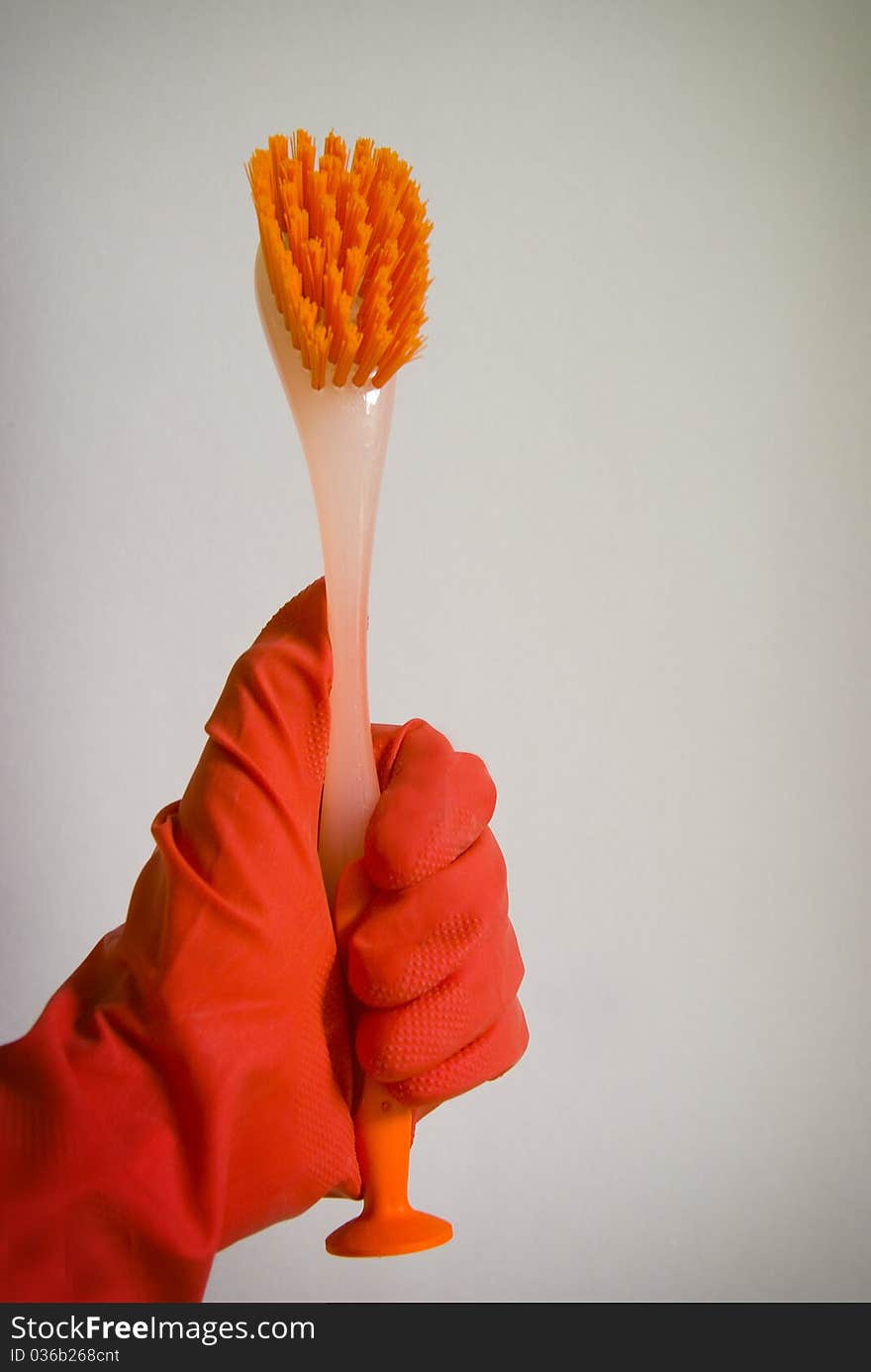 Hand in red rubber glove holding cleaning brush