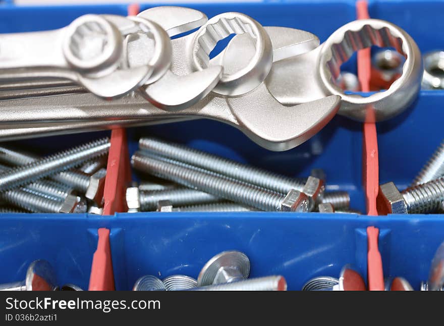 A set of spanners in front of toolbox of bolts and nuts. A set of spanners in front of toolbox of bolts and nuts