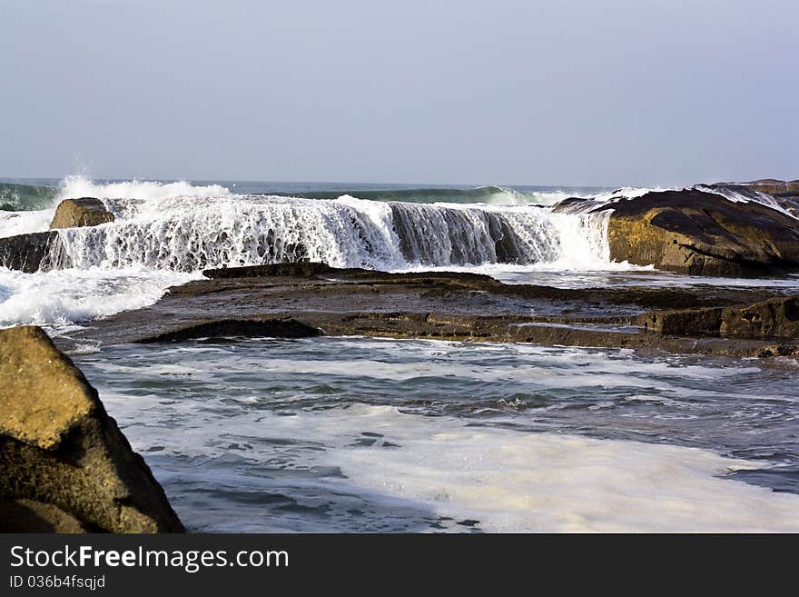 Sea waves run on coastal rocks