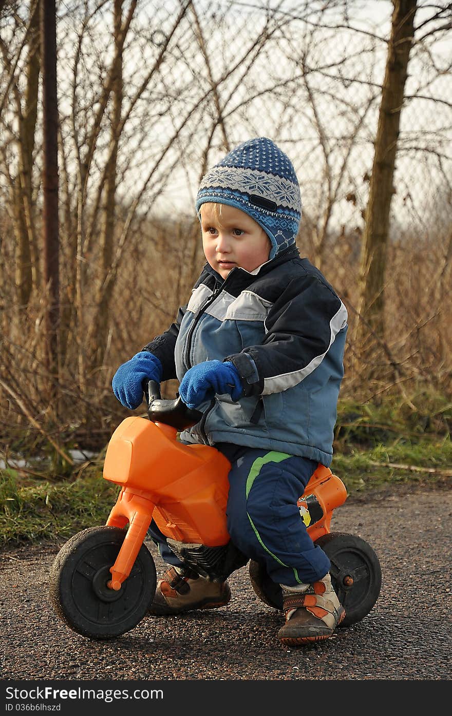 Little boy riding a toy motorbike during an afternoon walk. Little boy riding a toy motorbike during an afternoon walk