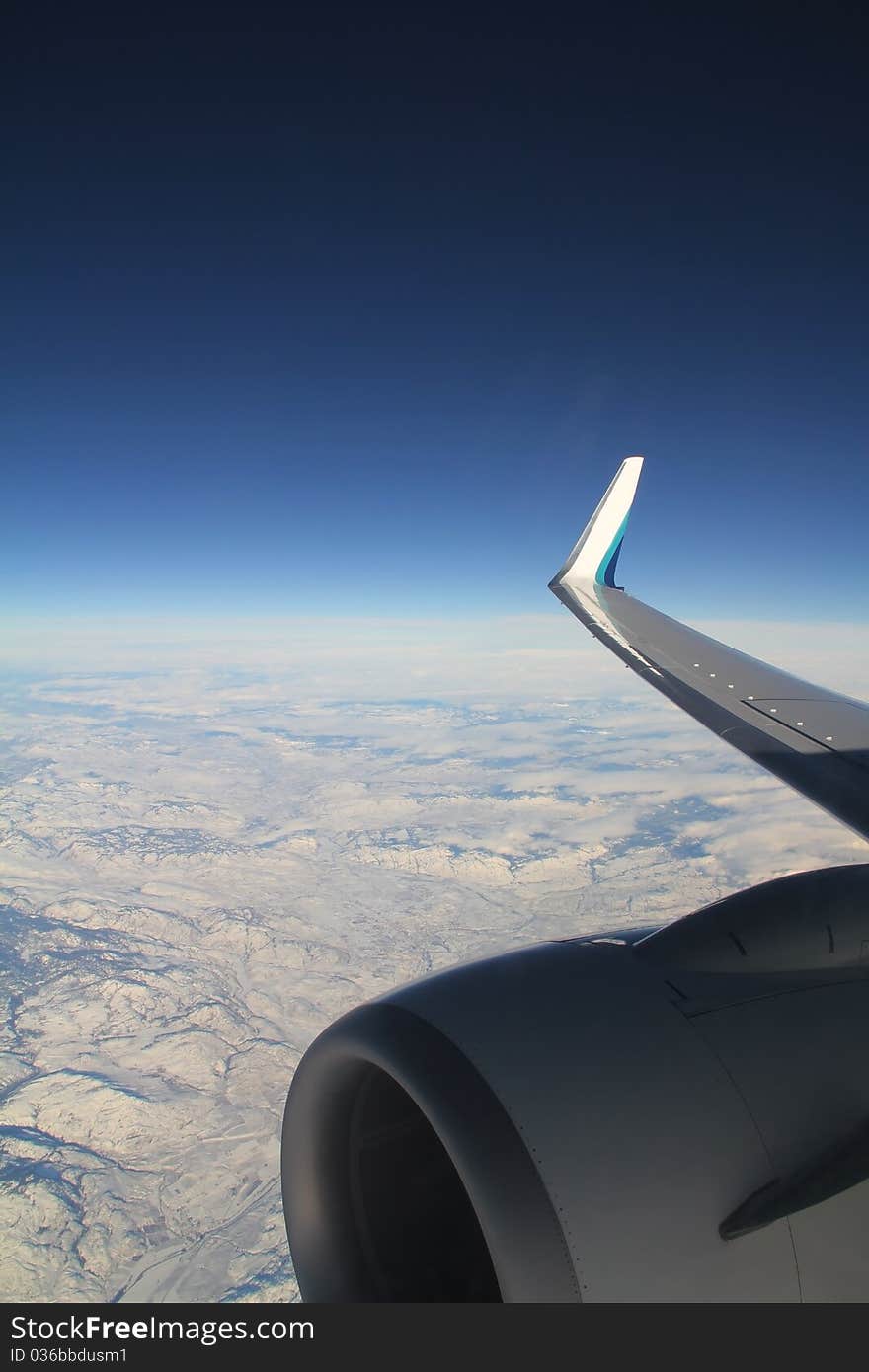 Aerial view of airplane engine and wing over snowy terrain