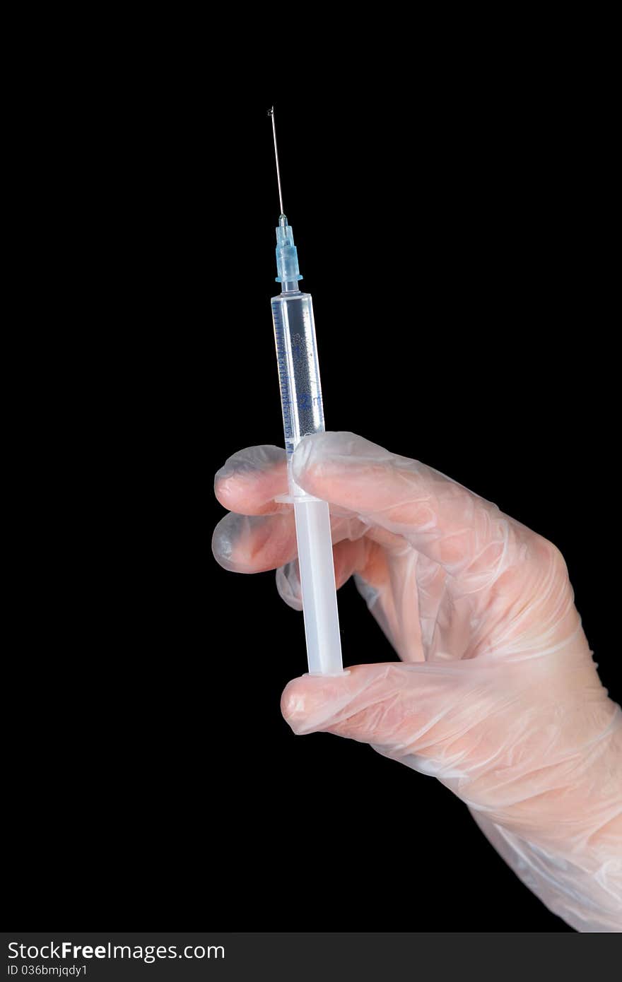 A hand in glove with syringe isolated on black. A hand in glove with syringe isolated on black