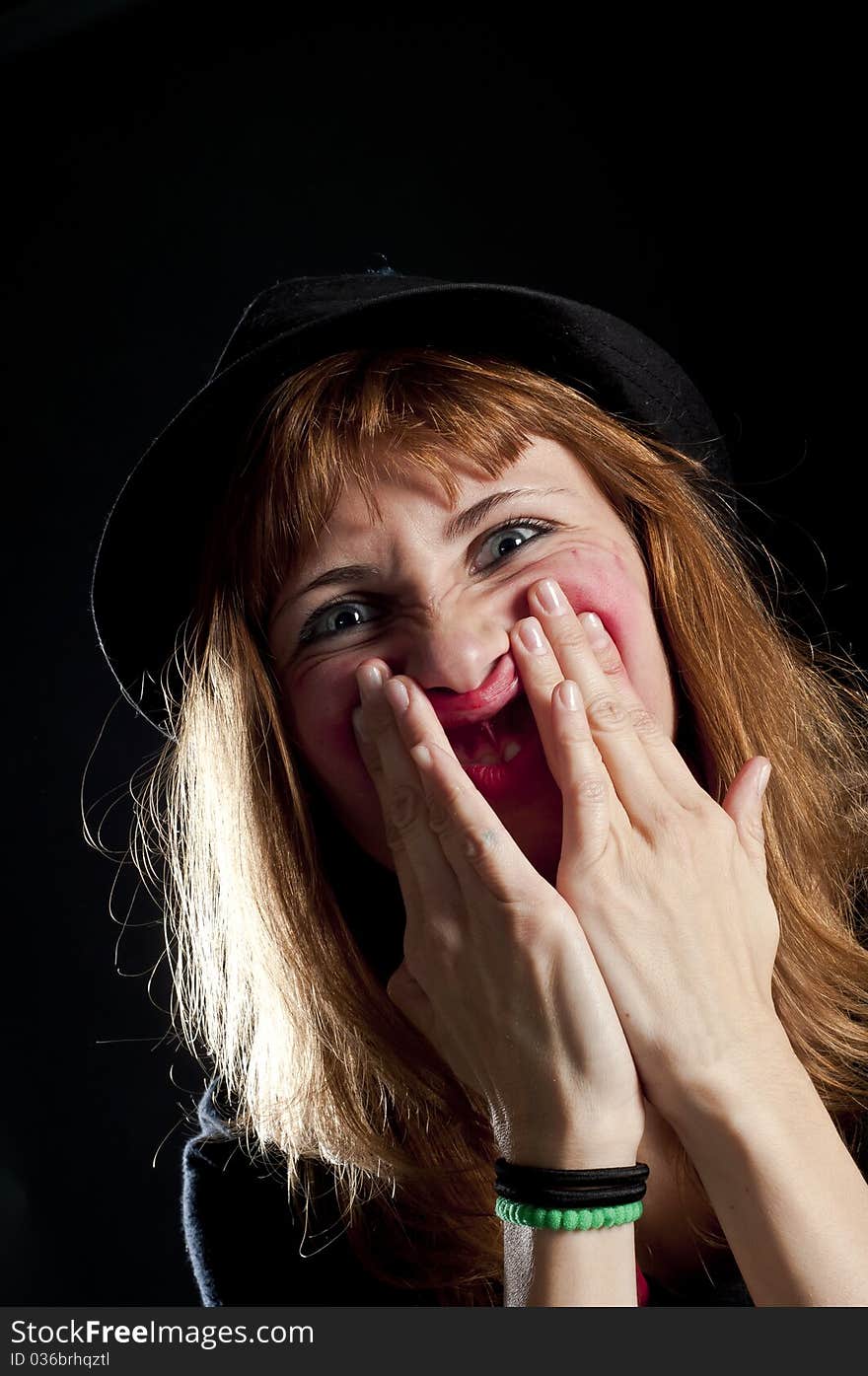 Blonde girl deforms the face with his own hands on black background