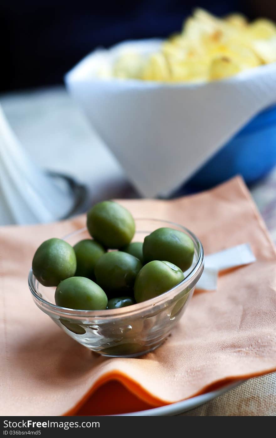 Green olives and chips on bar table