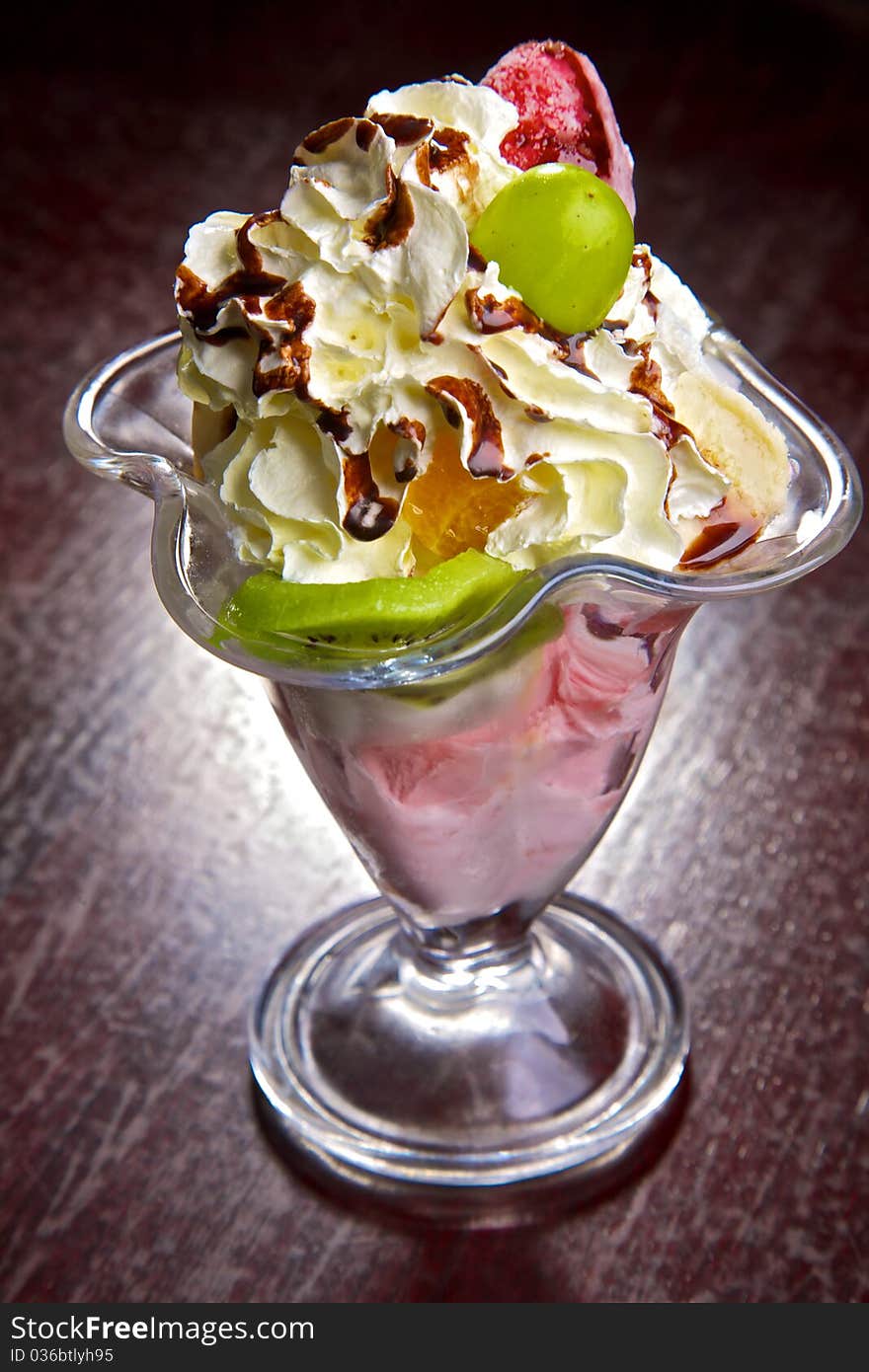 Fresh fruit in cream. A dessert from fruit and cream. Walnuts, a strawberry, a kiwi, pineapple, an apple, a banana, an orange in cream with chocolate