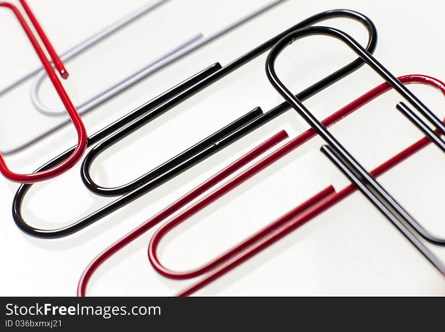 Black, red, and white paper clips sit on top of a desk