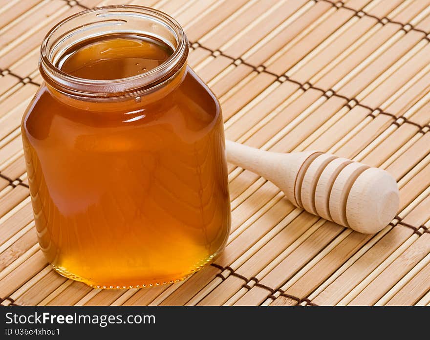 Glass pot of honey and wooden stick