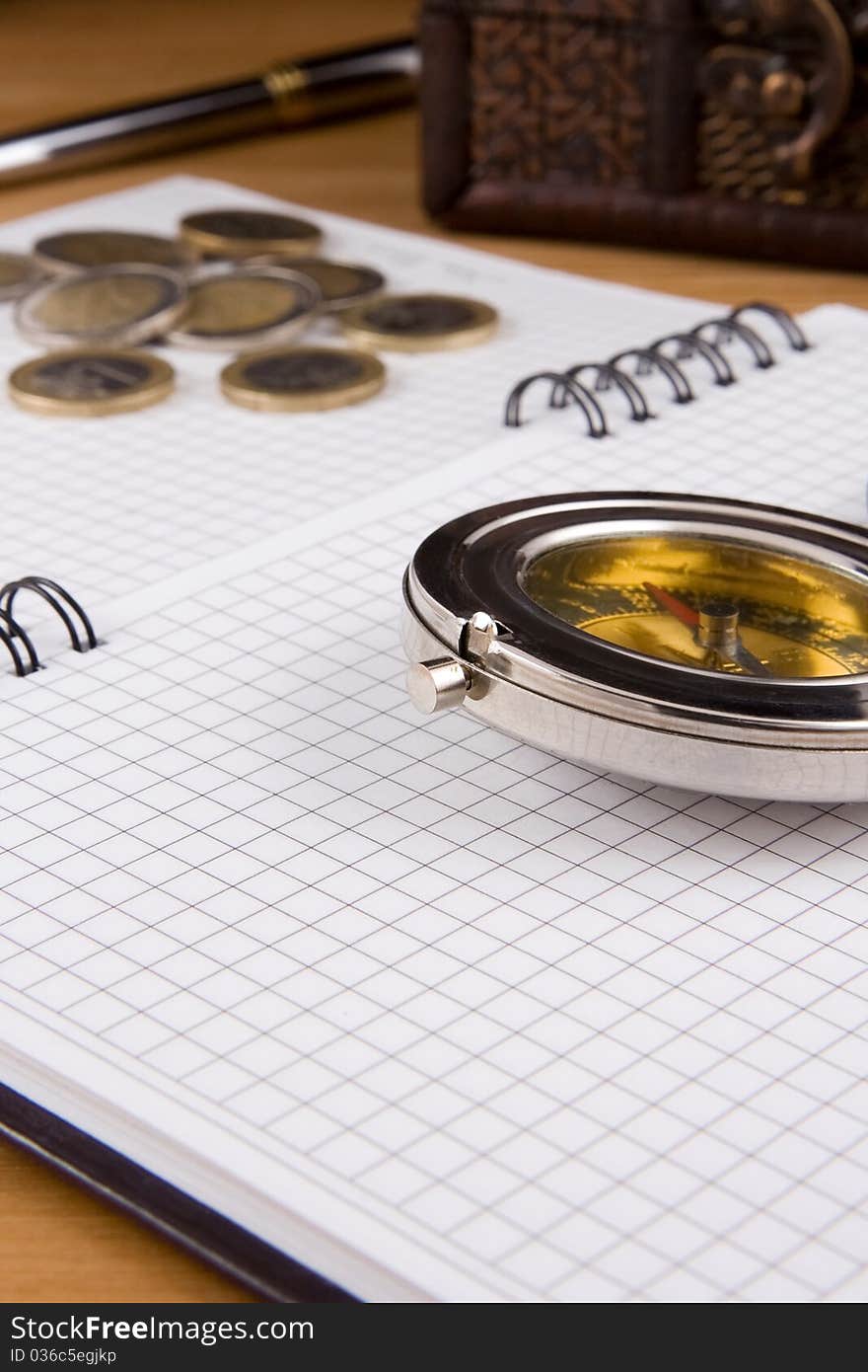 Compass, pen and coin on checked notebook. Compass, pen and coin on checked notebook