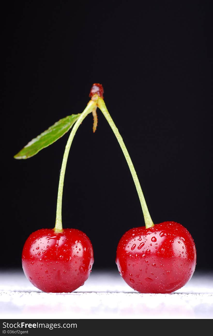 Two cherries against dark background