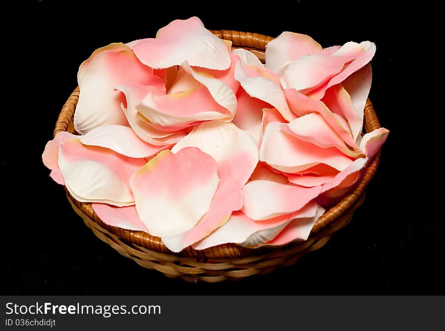 Artificial pink rose textile petals in basket on black. Artificial pink rose textile petals in basket on black