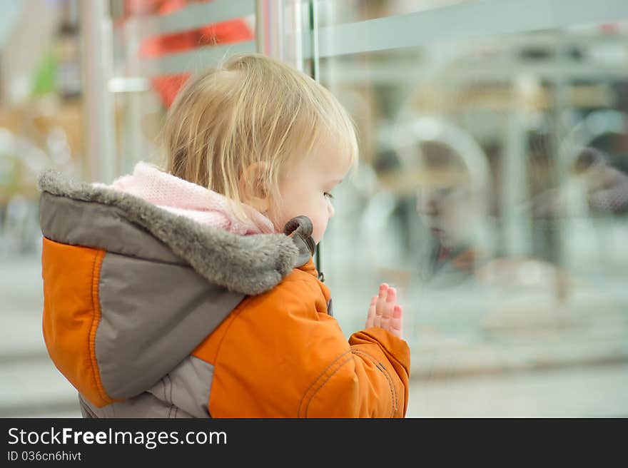 Cute adorable baby holds fence railing border in supermarket floor. Cute adorable baby holds fence railing border in supermarket floor