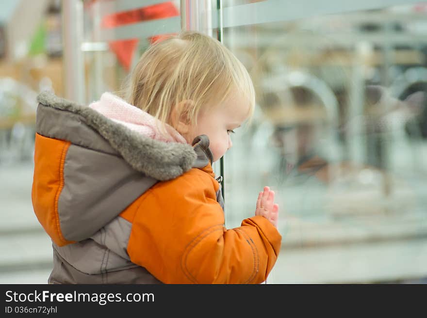 Cute adorable baby holds fence railing border in supermarket floor. Cute adorable baby holds fence railing border in supermarket floor