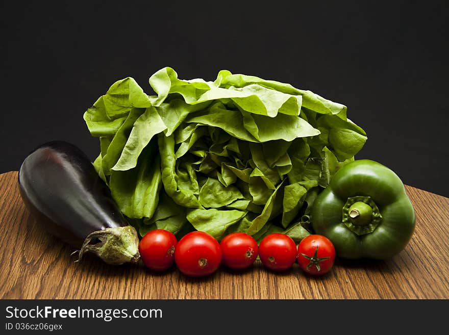 Paprikas, tomatoes, salad and aubergine onto black background. Paprikas, tomatoes, salad and aubergine onto black background