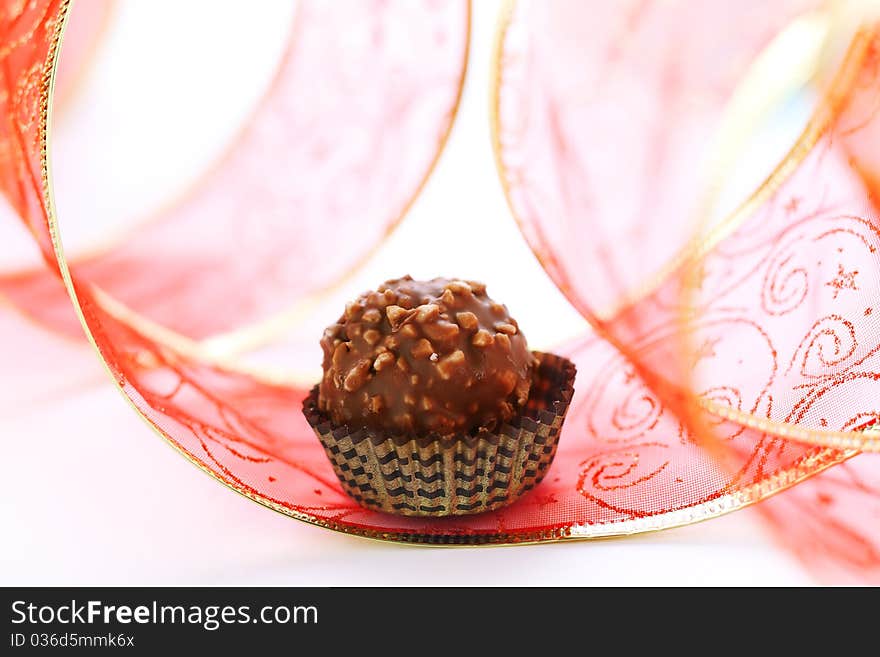 Chocolate truffle with red ribbon closeup