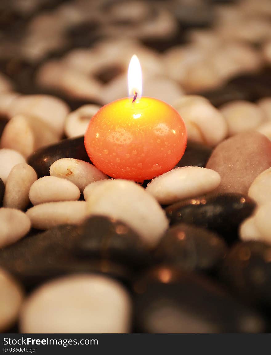 Orange candle on white and black stones